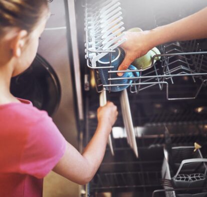 Dad and daughter loading the dishwasher in the Kitchen.